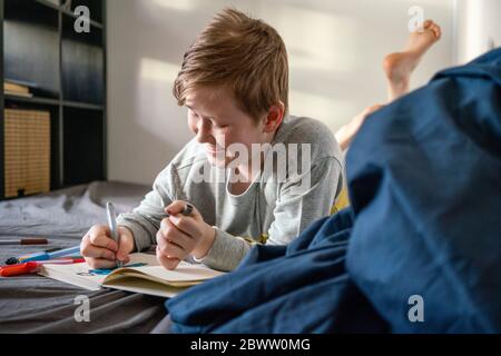 Garçon souriant allongé sur un tableau de lit Banque D'Images