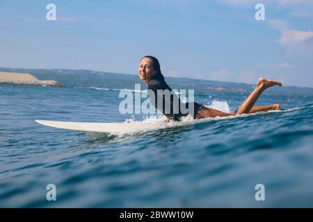 Bonne femme couchée à la planche de surf dans la mer, Bali, Indonésie Banque D'Images