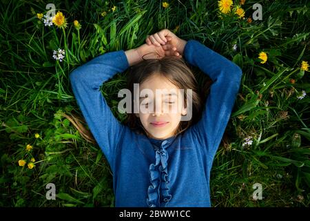 Portrait de fille avec les yeux fermés se relaxant sur un pré au printemps Banque D'Images