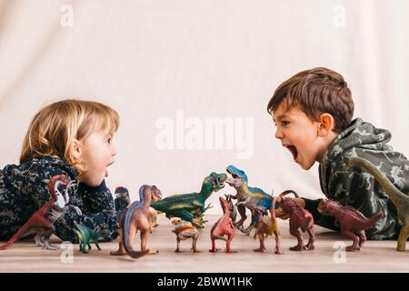 Frère et sa petite sœur jouant avec des dinosaures Banque D'Images