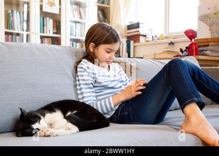 Fille assise sur un canapé avec une tablette numérique Banque D'Images