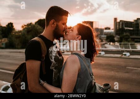 Jeune couple affectueux qui s'embrasse dans une rue au coucher du soleil, Berlin, Allemagne Banque D'Images