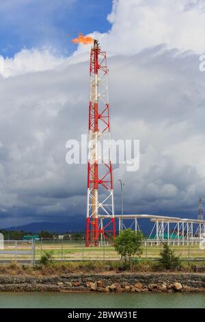 Une pile de torches peintes en rouge et blanc d'une usine pétrochimique de Kimanis, Sabah, en Malaisie, avec un ciel spectaculaire au-dessus de la chaîne de montagnes Crocker. Banque D'Images