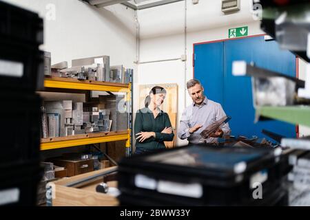 Homme d'affaires et femme d'affaires ayant une réunion de travail à une machine dans une usine Banque D'Images