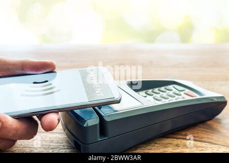 Paiement sans contact utilisant le concept de smartphone, personne tenant le téléphone contre le terminal de paiement POS Banque D'Images