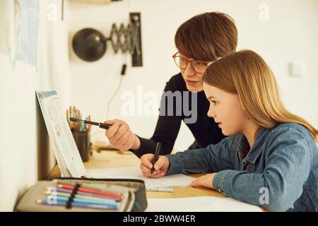 Mère aidant fille à faire ses devoirs à la maison Banque D'Images