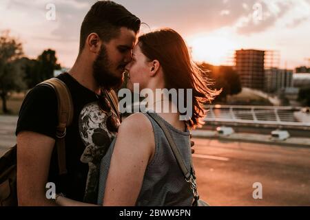 Jeune couple affectueux qui s'embrasse dans une rue au coucher du soleil, Berlin, Allemagne Banque D'Images