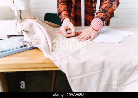 Gros plan de la femme épinglant le modèle de couture sur la table à la maison Banque D'Images