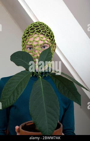 Portrait d'une jeune fille avec plante d'avocat en pot portant une coiffe verte crochetée Banque D'Images