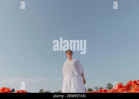 Portrait d'une femme souriante vêtue de champ de tulipe blanc debout Banque D'Images