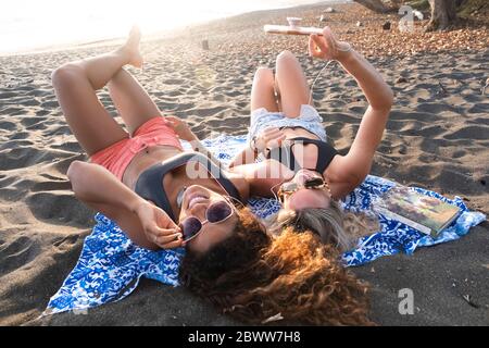 Deux femmes heureuses, couchée sur la plage, écoutant de la musique au téléphone, Costa Rica Banque D'Images