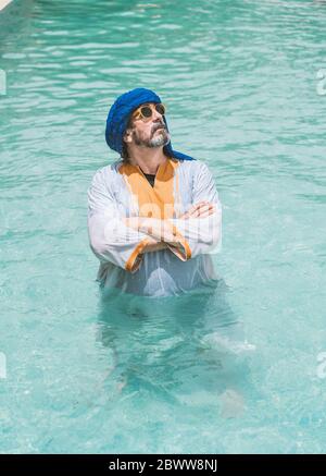 Homme au turban bleu, debout dans la piscine avec les bras croisés Banque D'Images