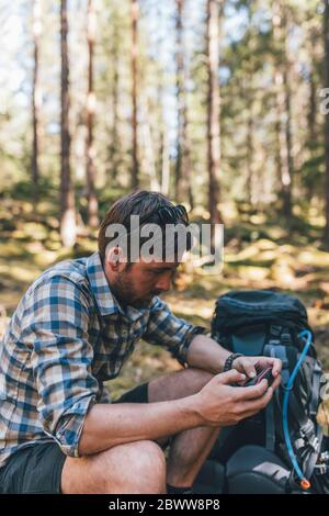 Jeune homme vérifiant le dispositif de navigation dans la forêt Banque D'Images