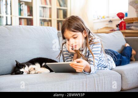 Portrait d'une fille allongé sur un canapé à l'aide d'une tablette numérique Banque D'Images