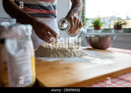 Vue rognée de l'homme en cuisine préparant la pâte Banque D'Images