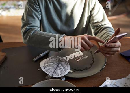 Fille à la maison utilisant un smartphone pour un tutoriel en ligne créatif Banque D'Images