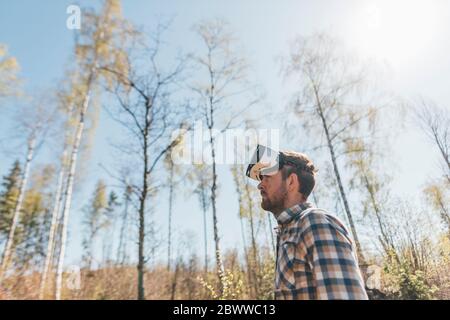 Jeune homme avec lunettes VR explorant la nature Banque D'Images