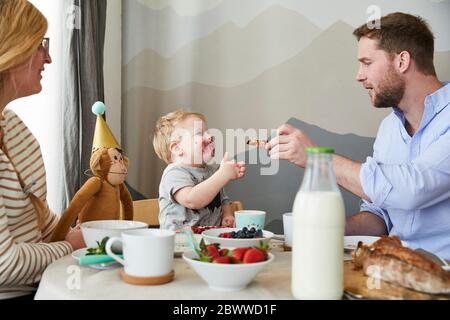 Petit garçon étalé avec ses parents à la table du petit déjeuner Banque D'Images