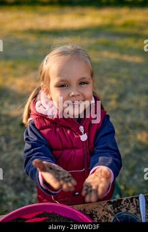 Portrait d'une fille souriante montrant ses mains sales du jardinage
