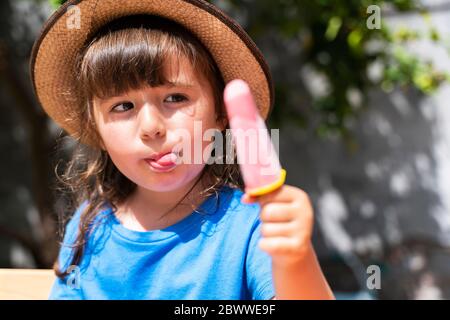 Portrait de la petite fille mangeant de la glace de fraise maison Banque D'Images