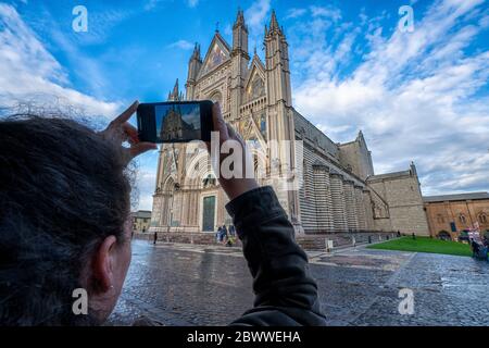Italie, Ombrie, Orvieto, vue sur l'épaule d'une femme photographiant la cathédrale d'Orvieto Banque D'Images