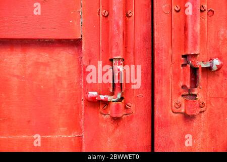 Fermez les anciens loquets métalliques sur le fond de fenêtre en bois rouge. Banque D'Images