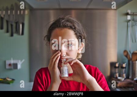 Enfant rhume des foins victime en utilisant un traitement par pulvérisation nasale pour un certain soulagement des symptômes de l'allergie. Banque D'Images