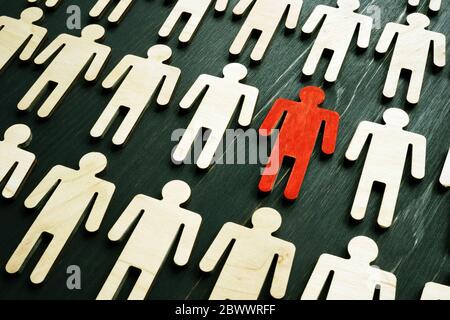 Concept d'inclusion et d'unicité. Figurine en bois rouge dans la foule. Banque D'Images