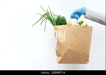 Le volontaire en gants bleus tient des légumes pour le don de nourriture pour aider les pauvres. Donner une boîte avec des aliments avec un endroit pour votre texte Banque D'Images