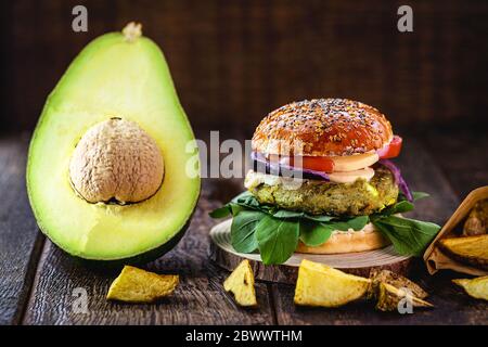 hamburger végétalien à base de légumes, sans viande ni gluten. Cuisine végétalienne avec avocat sur fond de bois rustique. Banque D'Images