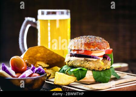 savoureux hamburger végétarien, fait maison sur une table en bois avec des légumes frais et une tasse de bière en arrière-plan, hamburger gastronomique Banque D'Images