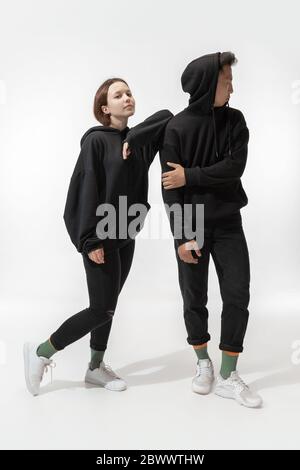 Ami. Un couple tendance isolé sur fond blanc. Femme et homme stylés posant dans des vêtements basiques et stylés, aussi bien adaptés aux deux. Concept d'égalité, inclusif. Banque D'Images