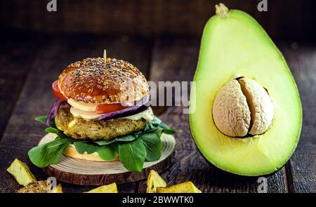 hamburger végétalien à base de légumes, sans viande ni gluten. Cuisine végétalienne avec avocat sur fond de bois rustique. Banque D'Images