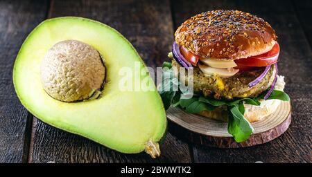 hamburger végétalien à base de légumes, sans viande ni gluten. Cuisine végétalienne avec avocat sur fond de bois rustique. Banque D'Images