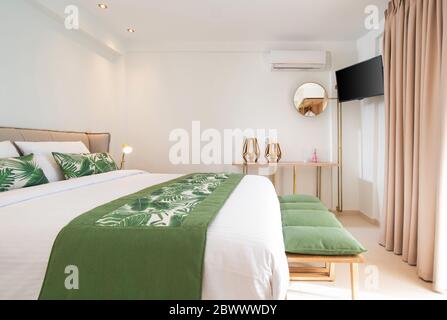 Intérieur moderne de style écologique de la chambre d'hôtel avec espace vide pour copier le mur. Vue latérale de la chambre blanche avec literie en feuilles de palmier vertes Banque D'Images