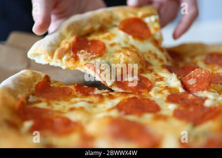 Gros plan sur les mains prendre une pizza avec des saucisses Banque D'Images