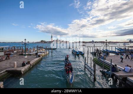 Gondoles amarrées et une remplie de touristes sur un voyage et des personnes se détendant le long de la Riva degli Schiavoni à Venise, Italie Banque D'Images