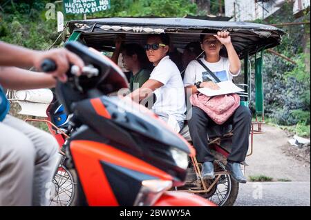 Le célèbre tricycle philippin ou tuk tuk (parfois appelé pousse-pousse) fait son chemin le long de la route principale très fréquentée allant dans Coron Town propre. Île Coron. Banque D'Images