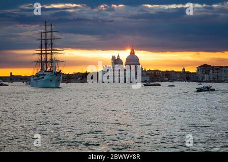 Trois voiliers à voile à mâts, MV Sea Cloud ll, quittant Venise, Italie, sous un coucher de soleil chaud, avec la basilique Santa Maria della Salute en arrière-plan Banque D'Images