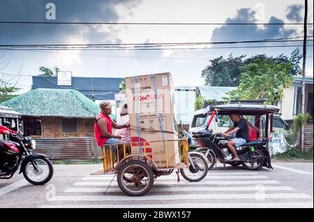 Le célèbre tricycle philippin ou tuk tuk (parfois appelé pousse-pousse) fait son chemin le long de la route principale très fréquentée allant dans Coron Town propre. Île Coron. Banque D'Images