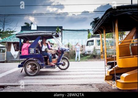 Le célèbre tricycle philippin ou tuk tuk (parfois appelé pousse-pousse) fait son chemin le long de la route principale très fréquentée allant dans Coron Town propre. Île Coron. Banque D'Images