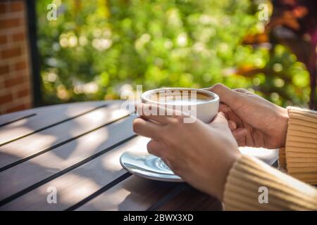 Main en gros tenant une tasse de café sur une table en bois Banque D'Images