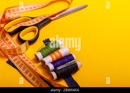 Pose plate de rouleaux de fils de couleur et de ciseaux pour coudre le fond jaune. Couture et travaux d'aiguille. Outils pour la couture et la main: Fil, scas Banque D'Images