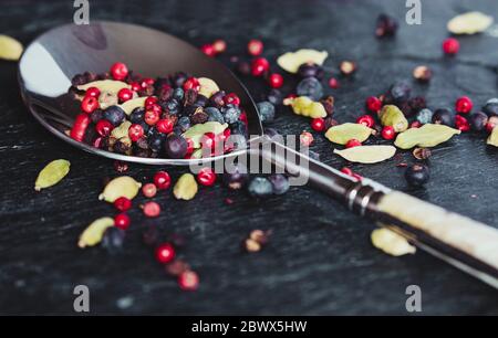 Détail magnifique d'une cuillère et épices poivre rouge, cardamome, genévrier. Banque D'Images