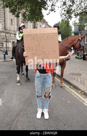 LONDRES, Royaume-Uni - 3 JUIN 2020 : une femme fait un geste offensant en portant un panneau de protestation devant la police lors d'une manifestation Black Lives Matter Banque D'Images