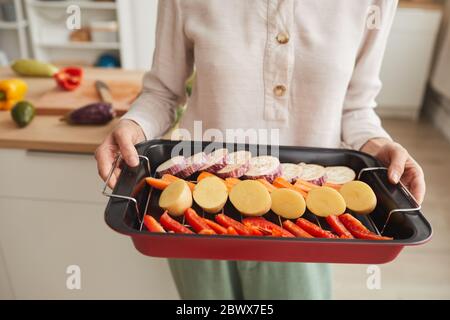 Gros plan de la femme tenant la poêle avec les légumes elle préparant des légumes du gril Banque D'Images