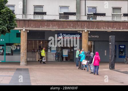 Coventry Ciy/ Royaume-Uni - 3 juin 2020 : longue file d'attente de personnes observant des distances sociales allant à la société de construction nationale pendant qu'elle pleut. Banque D'Images