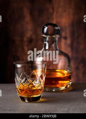 Single-malt Scotch Whisky en verre et décanter sur une surface en pierre et un fond en bois Banque D'Images