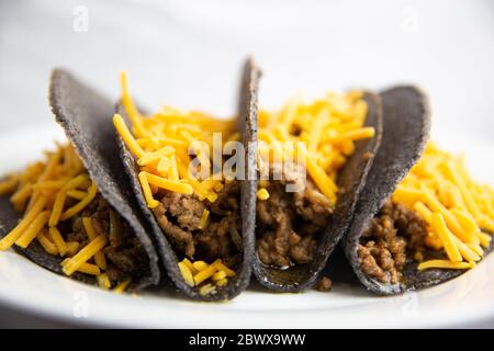 Tacos au maïs bleu coquille dure classique avec bœuf haché et fromage sur plaque blanche Banque D'Images