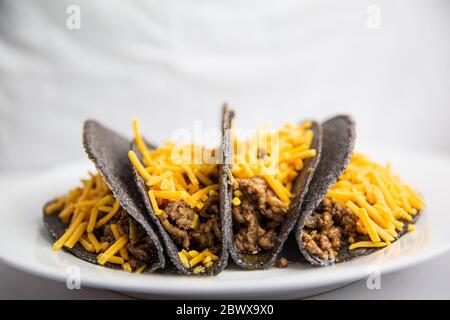 Tacos au maïs bleu coquille dure classique avec bœuf haché et fromage sur plaque blanche Banque D'Images